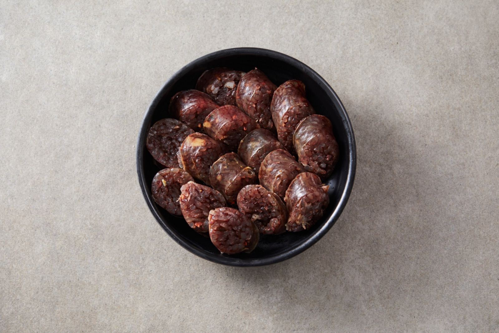 Sliced Byeongcheon-style sundae in a bowl, showing the dense blood-and-barley filling
