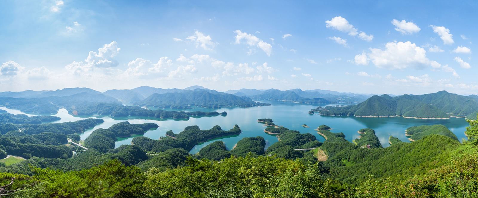 A panoramic view over Chungju Lake, blue water winding between green forested hills and islands