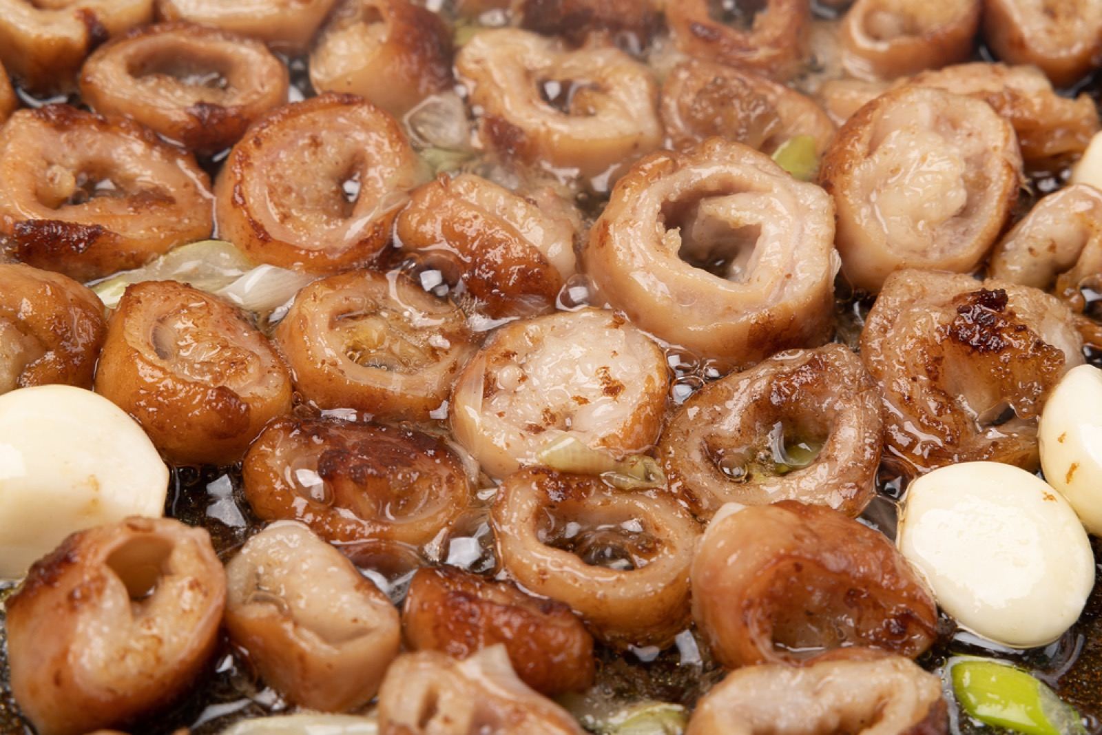 Close-up of glossy grilled makchang (pork intestine) pieces sizzling on a tabletop grill in Daegu