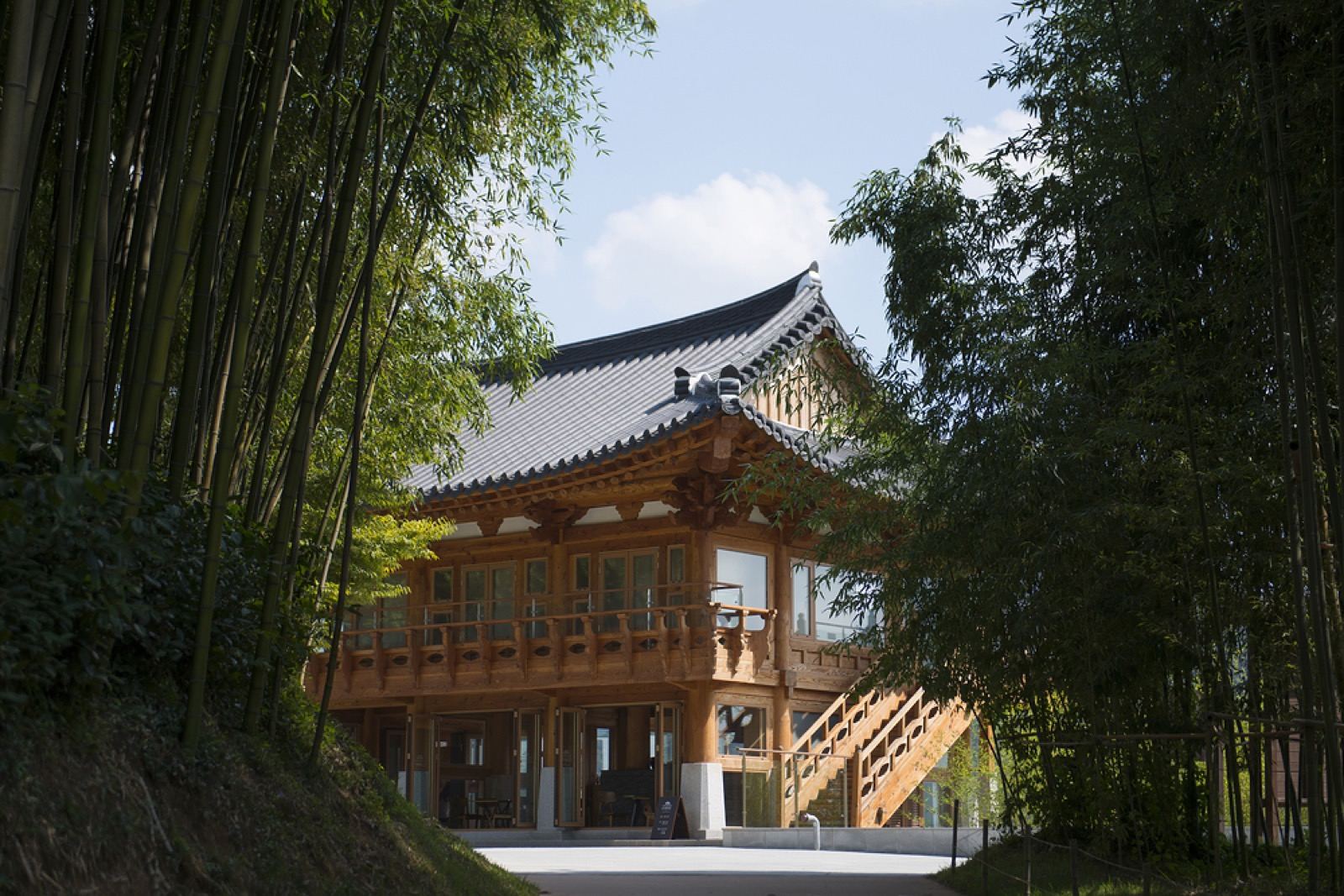 A wooden walking path leading through tall green bamboo at Juknokwon