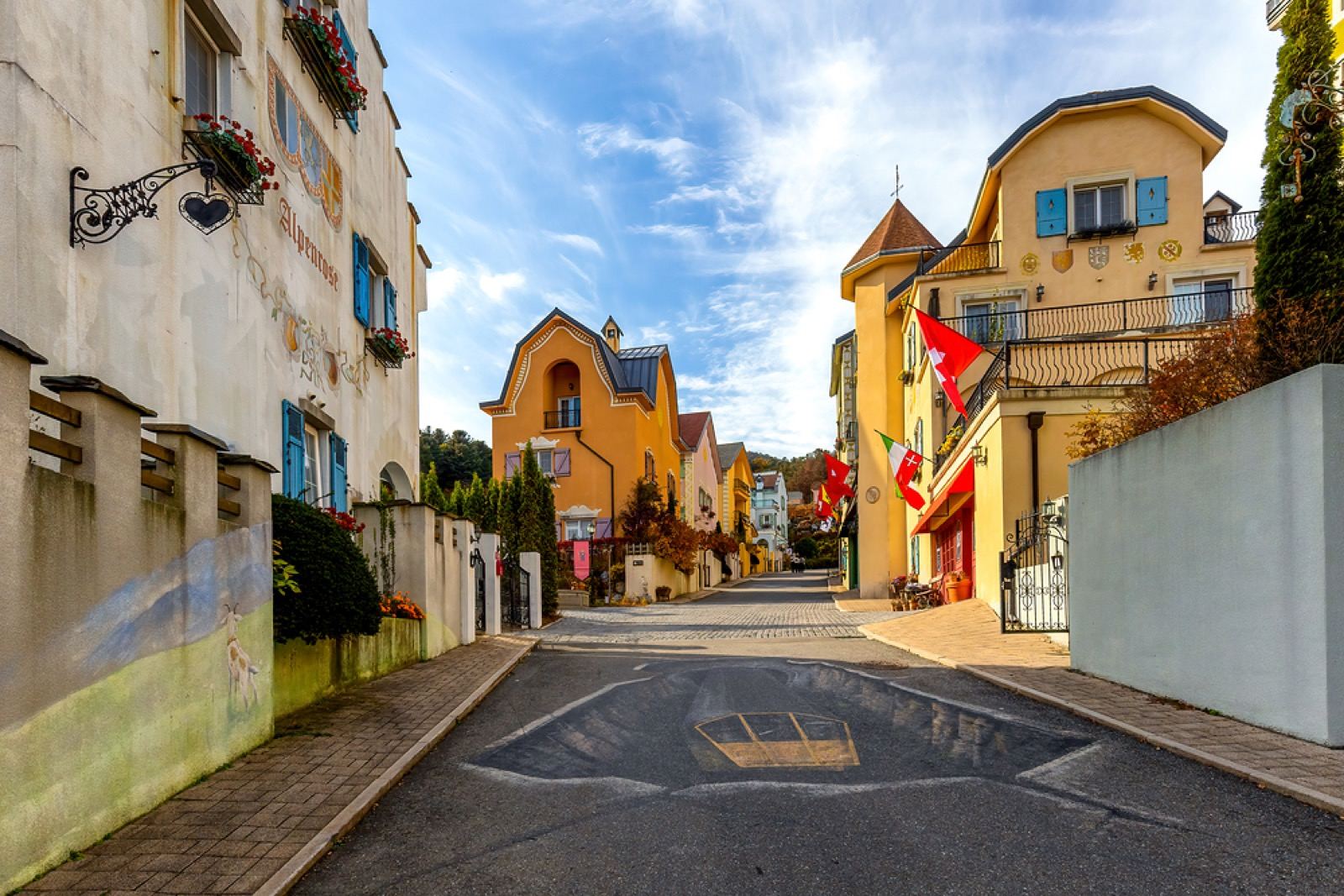 A lane of brightly painted French-style cottages with flags at Petite France in Gapyeong