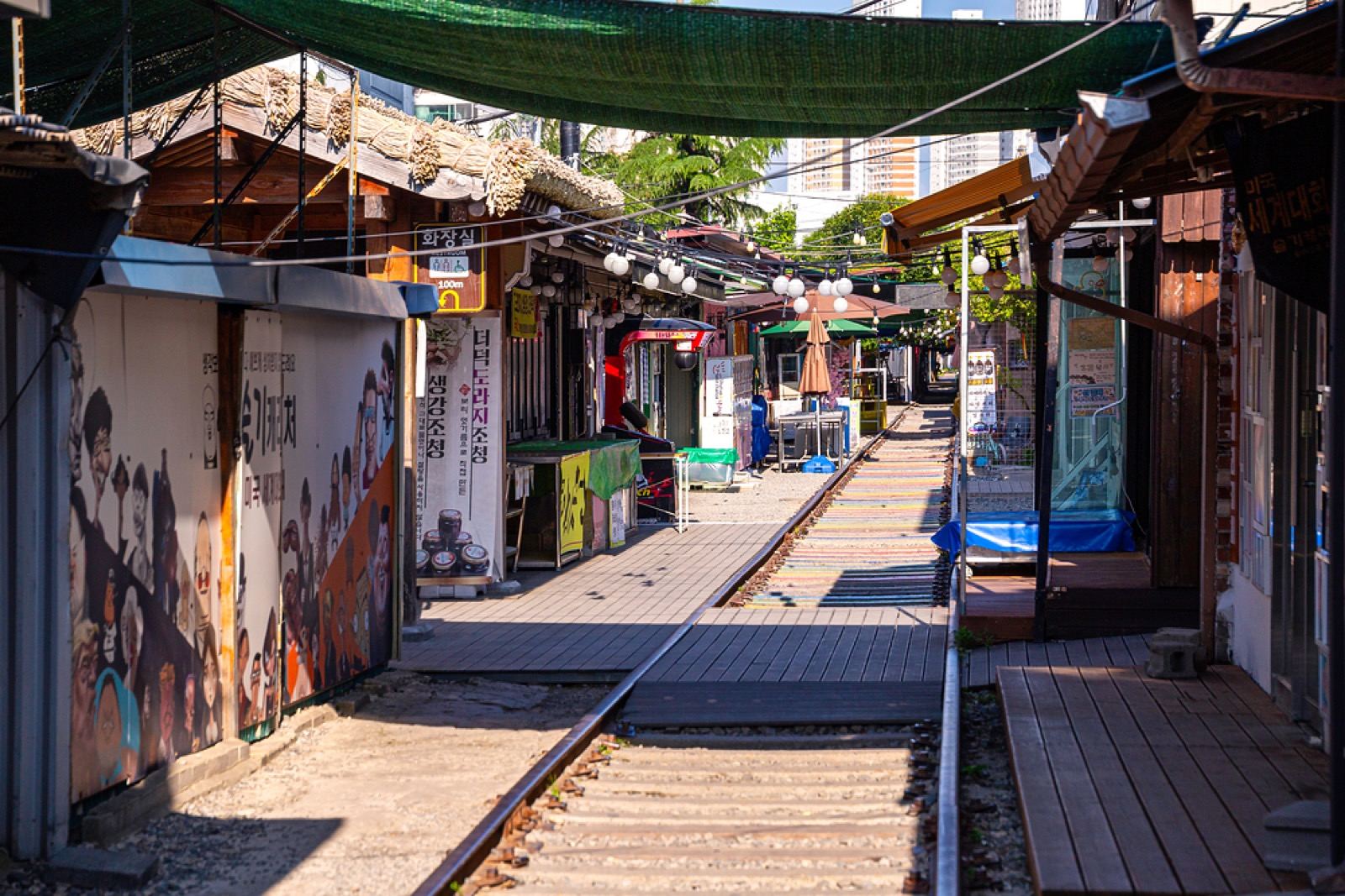 Old shopfronts and murals lining a disused railway track at Gyeongam-dong Railroad Village in Gunsan