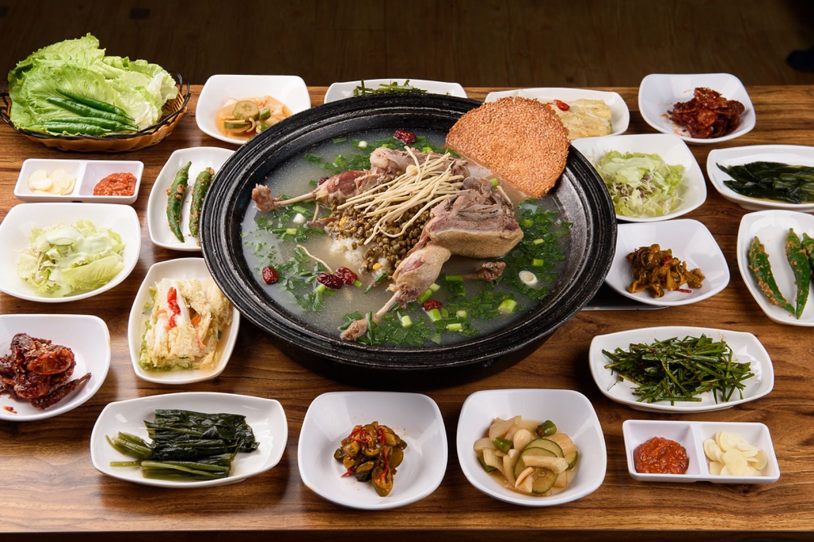 A large pot of Gwangju-style oritang (duck soup) with minari and a spread of side dishes