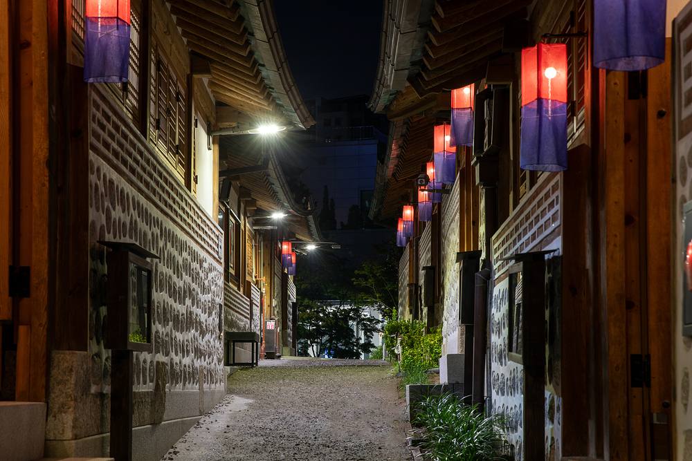 A hanok alley glowing with lanterns at night
