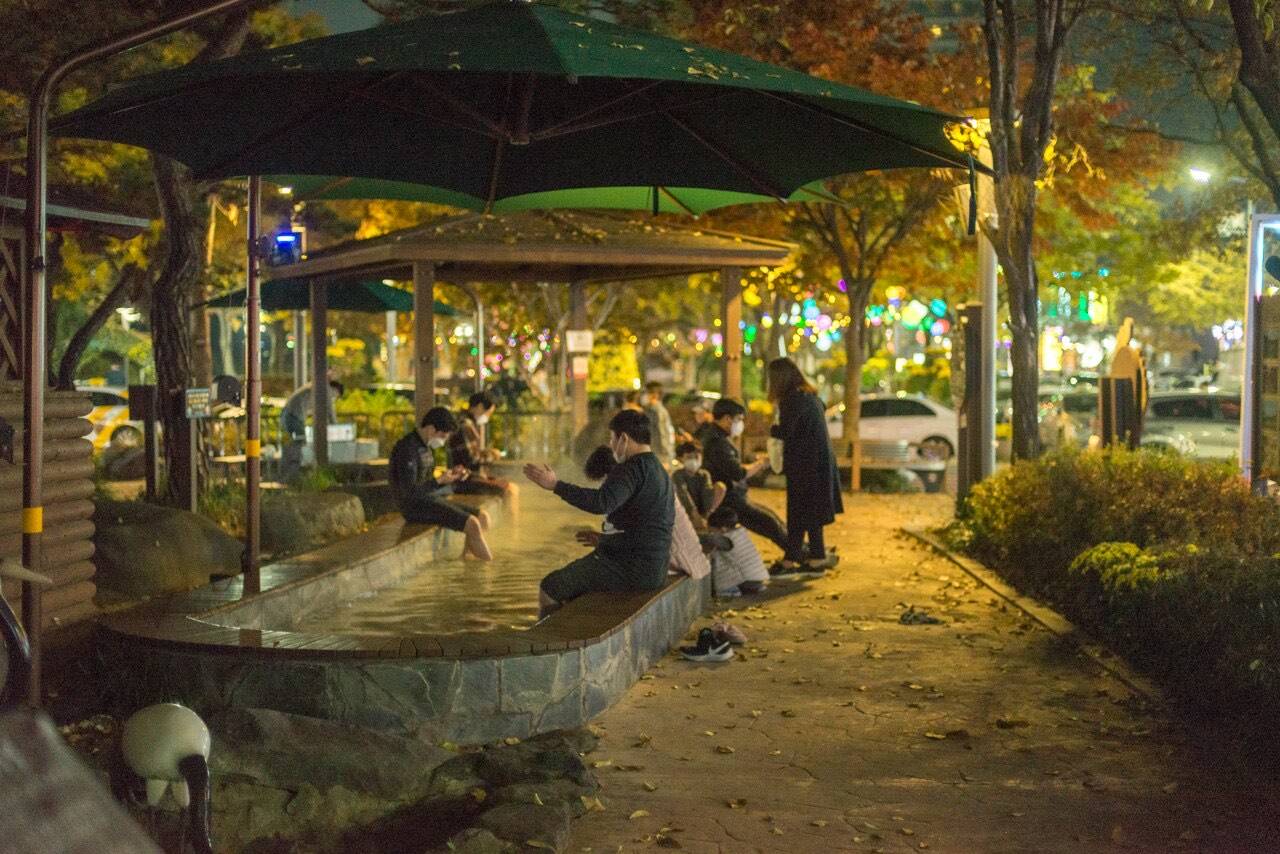 An outdoor public foot spa lit up at night in Yuseong hot-spring district