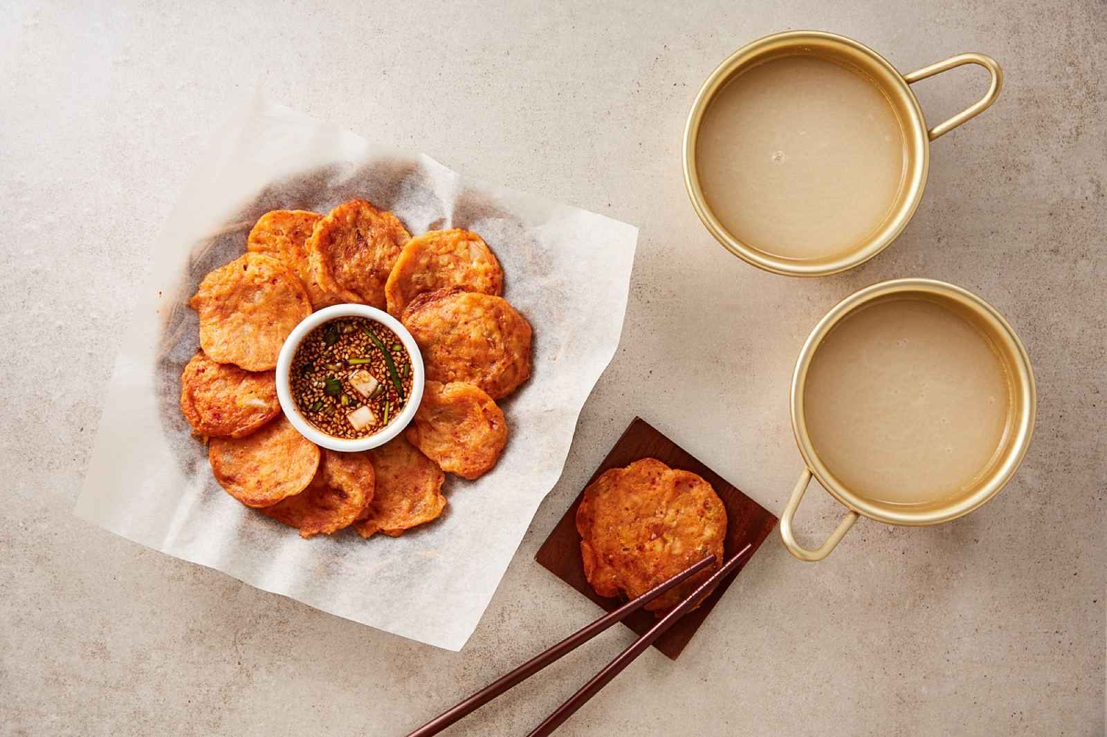 A brass kettle of makgeolli surrounded by many free side dishes on a table