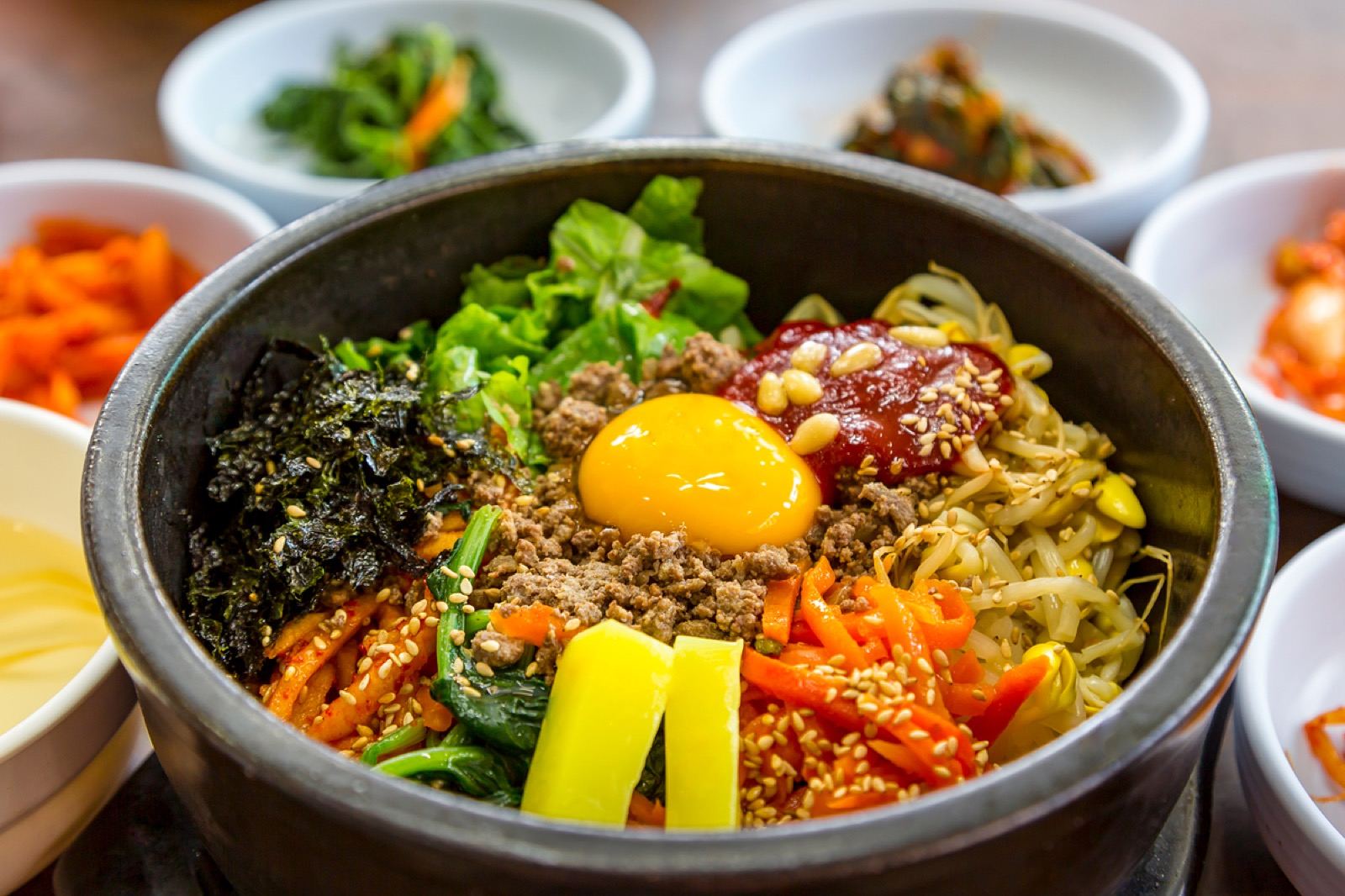 A mixed bibimbap bowl with egg, vegetables, beef and gochujang, ready to eat