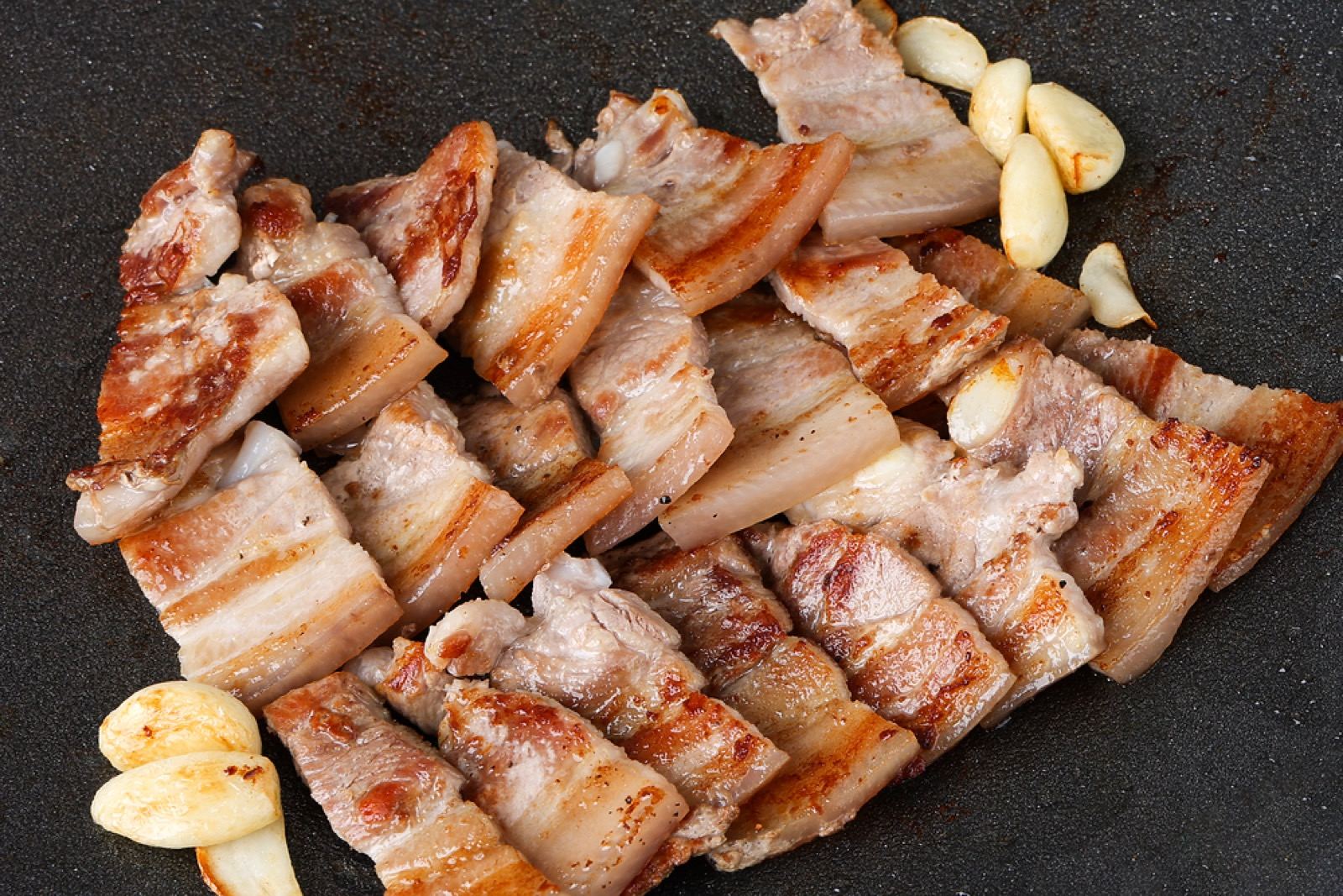 Pork belly grilling on a tabletop grill at a Korean BBQ restaurant