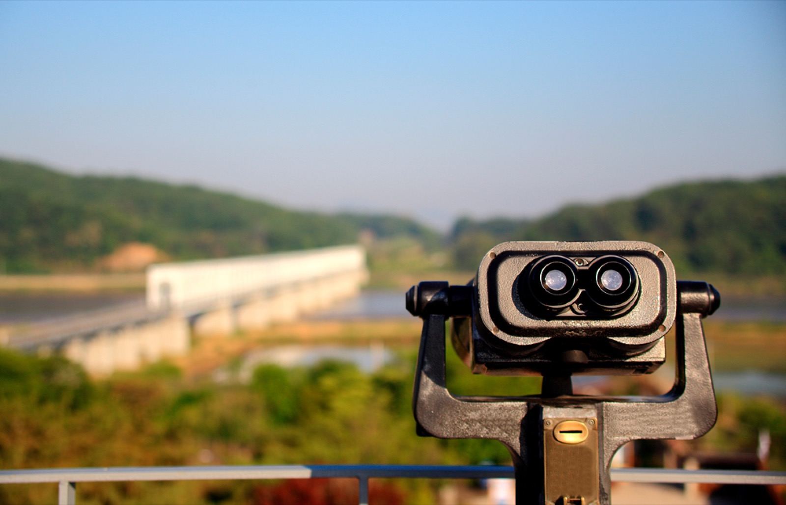 Tourist binoculars on an observation deck looking out over a bridge and river toward the DMZ