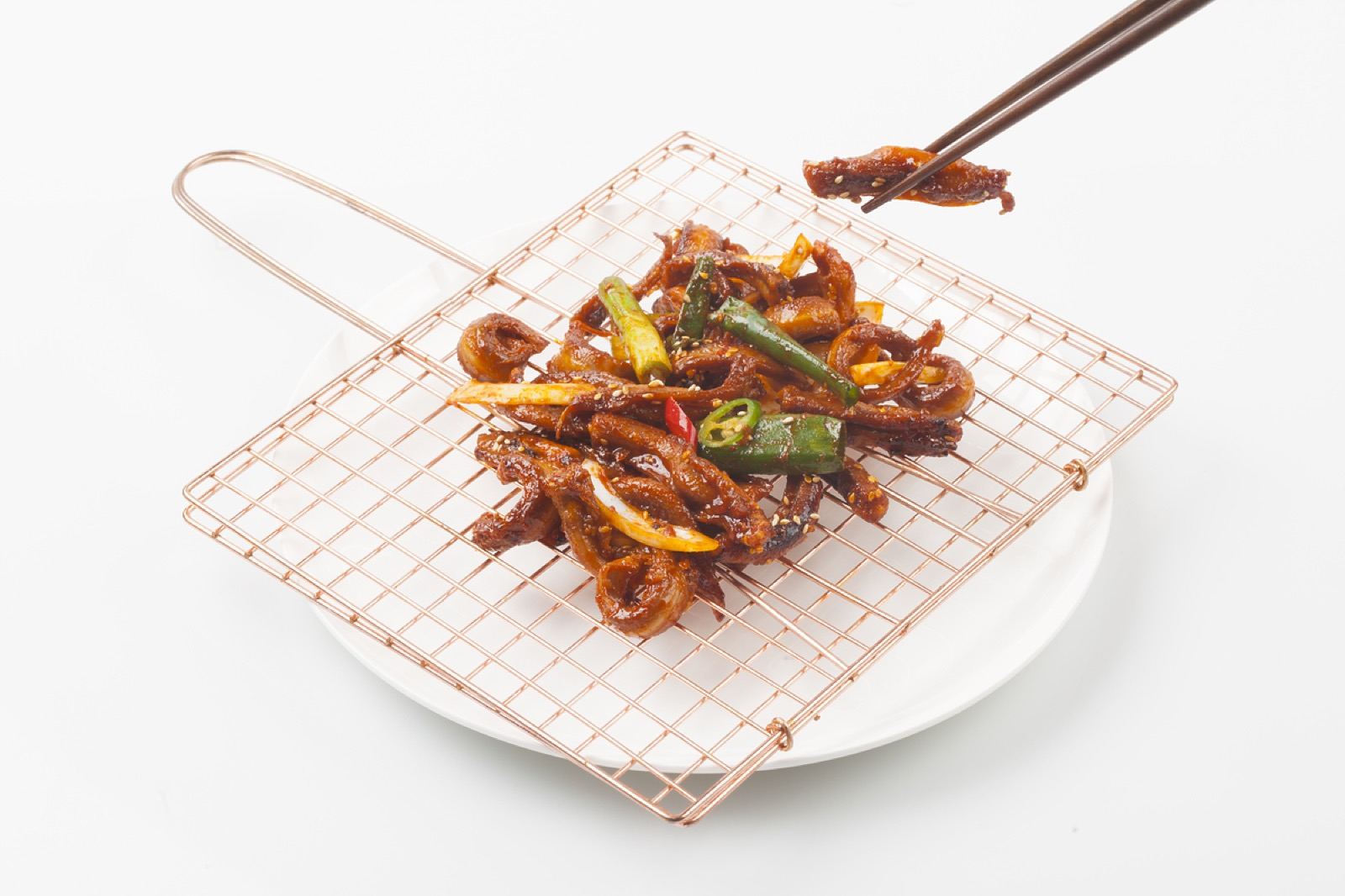 Spicy grilled gomjangeo (hagfish) with green chilies and sesame on a copper grill rack