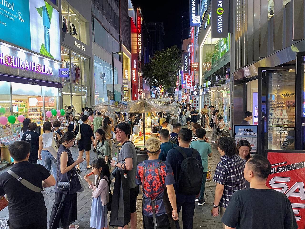 Neon signs and crowds at a busy Korean shopping street at night