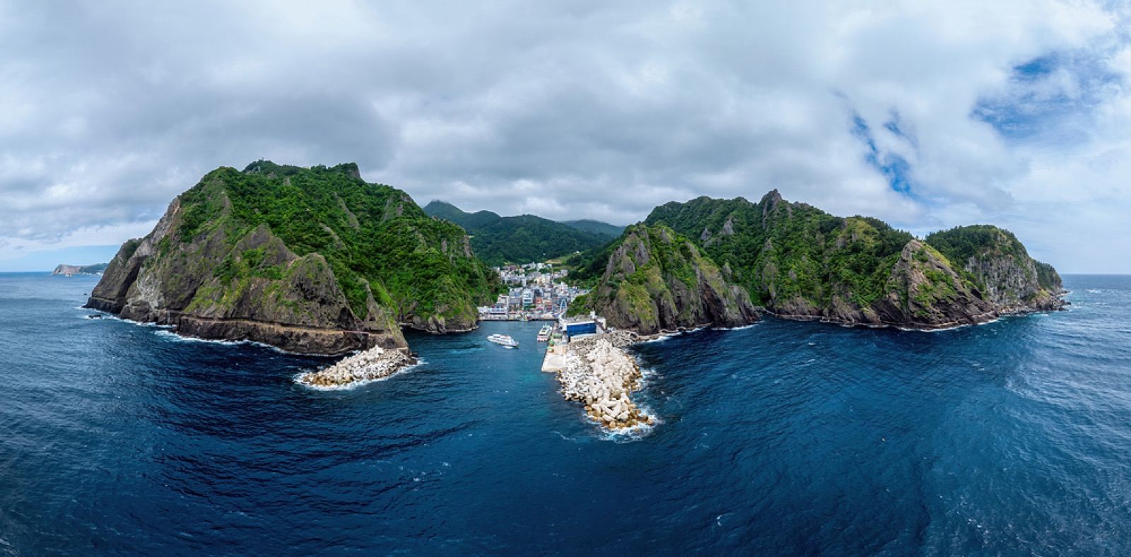 Aerial view of Ulleungdo's twin rugged peaks and a small harbor between steep cliffs